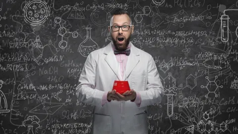Photo of Jason Lindsey holding a beaker filled with red liquid. Also features a blackboard background.